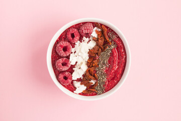 Top view of smoothies bowl with raspberries and natural superfoods on the pink background