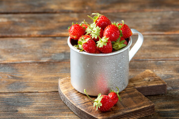 Strawberries in a metal mug on a brown wooden table