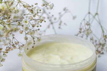 Natural cosmetic products with white small flowers on white background. Natural beauty product concept. Gypsophila, selective focus