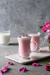 Rose moon milk in glass cups on grey background. Close up. Vertical format.