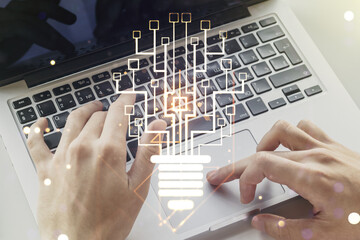 Double exposure of creative light bulb hologram with chip and hands typing on laptop on background, idea and brainstorming concept
