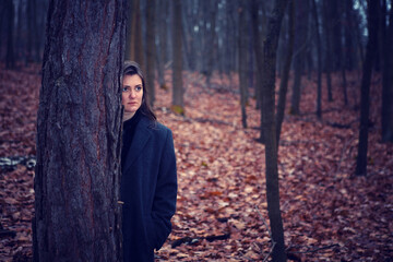 young brunette woman standing alone in the middle of a forest