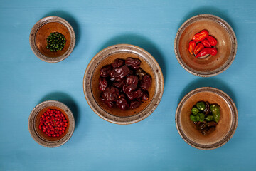 Bowls and plates with ripe and unripe chili peppers (Habanero, Chiltepin and Jolokia). Bloue background and yellow gingko leaves branch.