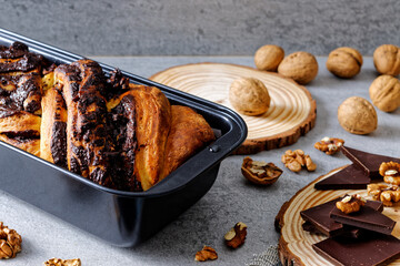 Krantz cake with chocolate and nuts filling in black baking tin mold. Yeast-risen dough twisted...