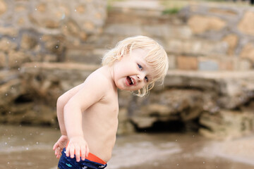 Little boy walking and playing on the beach of the sea. Summertime, vacation, travel, nature concept.