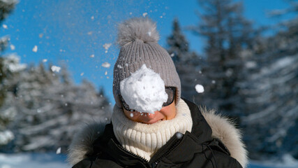 PORTRAIT: Smiling female tourist gets hit in the face by a fluffy snowball.