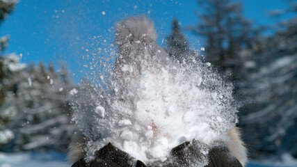 CLOSE UP: Fluffy snowball splatters as it meets unrecognizable woman's face.