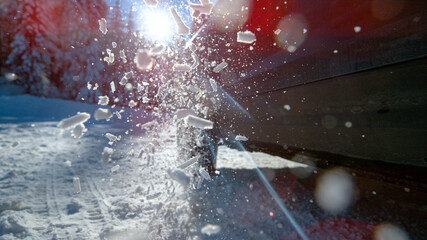 CLOSE UP: Powerful SUV's wheels spinning in place and spewing out pieces of snow