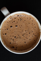 Cup of coffee with foam on black background