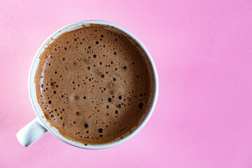 Cup of coffee with foam on pink background