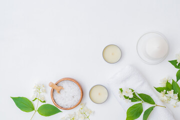 Flat lay spa composition with jasmine flowers, sea salt in bowl, towels on a white background