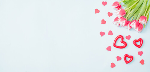 Flat lay valentines day frame with pink tulips and and red heart on a light green background