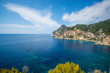 Bright blue azure Ionian sea near the rocks on the background bright green bushes in Corfu island Greece