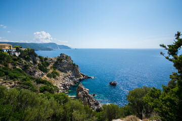 Fototapeta na wymiar View on the bright blue azure sea and rocks and green trees and blue sky from the mountain at in Corfu island Greece