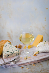 Cheese board with wine, nuts on light background.