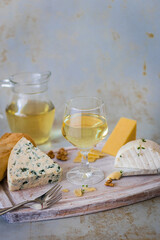 Cheese board with bread, nuts and glass of white wine. Light background.