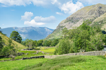 Fototapeta na wymiar A view towards Blencathra or Saddleback through St John's in the Vale in the English Lake District National Park under a blue sky with fluffy clouds on a sunny summers day