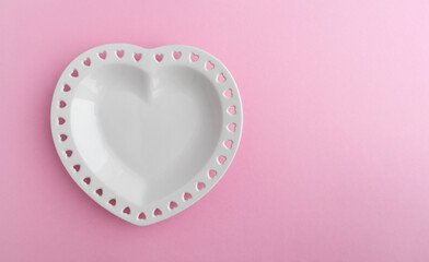 Heart shaped porcelain plate on a pink background with space for text. Template for invitation, postcards for the holiday
