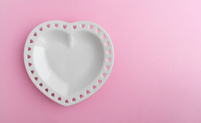 Heart shaped porcelain plate on a pink background with space for text. Template for invitation,...