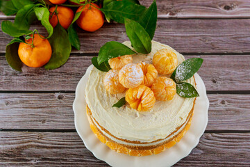 Cake with fresh mandarins and green leaves.
