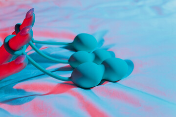 Woman holding anal balls in bed close-up.