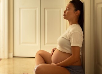 A sad pregnant woman sitting alone at home stressed. Depression.