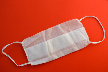 sterile disposable mask for respiratory protection from coronavirus infection. white mask made of fine materials with white long ties. sterile mask on bright red background