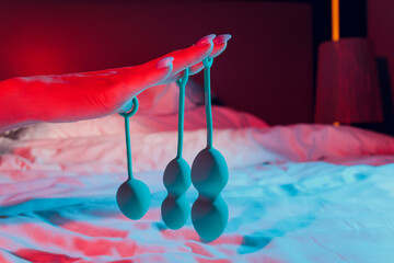Woman holding anal balls in bed close-up.