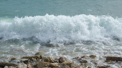 Mediterranean rocky beach with wavy sea in a cloudy morning