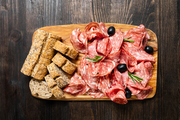 Traditional Italian antipasti salami on a wooden plate, served with olives. Food for an aperitif and dinner lunch in the restaurant. 