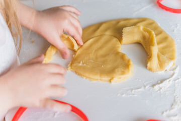 Obraz na płótnie Canvas Little girls, sisters cooking homemade heart shaped cookies for valentine's day. Holiday for all lovers. Gift, surprize for mom. Red molds, rolling pin, flour, dough.Handmade family, bakery with kids
