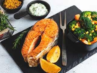 roast baked fish steak salmon, trout with broccoli and carrots, on plate