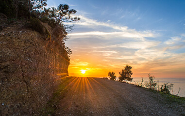 A mountain road, at the end of which is sunset and sea, sky and clouds and way, Algeria