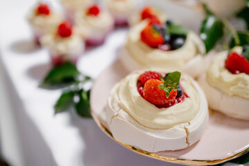 Mini Pavlova meringue cake with fresh berries on a pink and golden plate