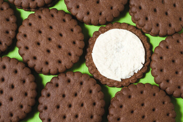 Texture background of rows of chocolate-cream cookies. One cookie with white buttercream.