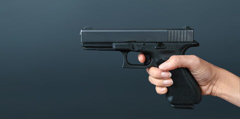 Hands holding gun isolated on dark background. Shooting with a pistol. Banner concept, copy space for your text. 