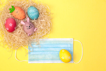 Easter Flat lay with a medical face mask, colorful eggs lie in the hay on a white tray. Holiday...