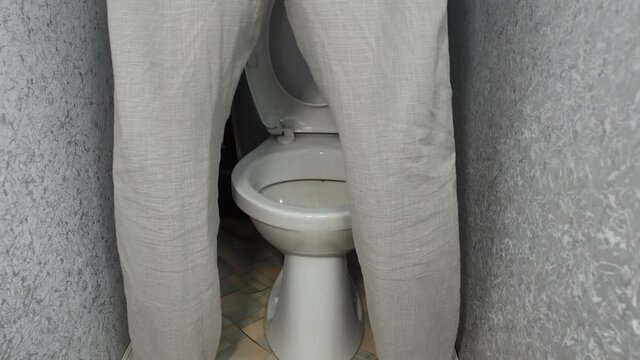 Elderly man with adenoma urinates standing up and stains edge of toilet bowl.