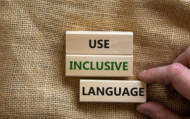 Use inclusive language symbol. Wooden blocks with words 'Use inclusive language'. Beautiful canvas background, businessman hand. Business and use inclusive language concept. Copy space.