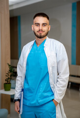 Portrait of a doctor or medical specialist wearing scrubs. Vertical portrait. Clinic corridor background. Medic poses to the camera.