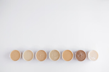 top view of containers with homemade nut or peanut butter on white background