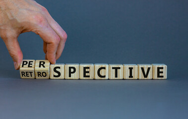 Perspective or retrospective symbol. Businessman hand turns cubes and changes word 'retrospective' to 'perspective'. Beautiful orange background. Business and perspective concept. Copy space. - obrazy, fototapety, plakaty