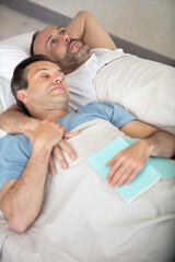 gay couple lying on bed top view