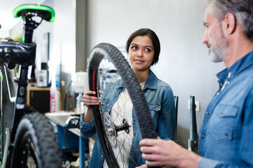 Fototapeta na wymiar woman checking bicycle tire in shop factory