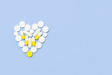 Heart symbol made of pills on a blue background.