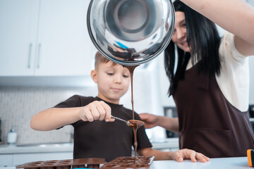happy mother and kid making chocolate candies or sweets at home modern kitchen