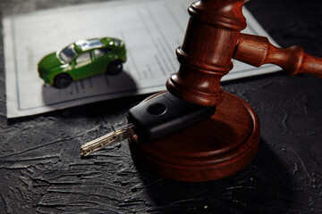 Wooden hammer and toy car with car keys. Insurance, court case close-up.