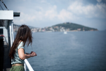 Fototapeta na wymiar Young long haired girl on sea ship. Relaxation during summer vacation