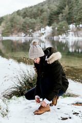 Woman tying shoelaces on the shore of a swamp