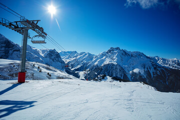 Fototapeta na wymiar Ski lift, mountain peaks and clean empty trails in Pralognan-la-Vanoise range over snowy tops in French Alps